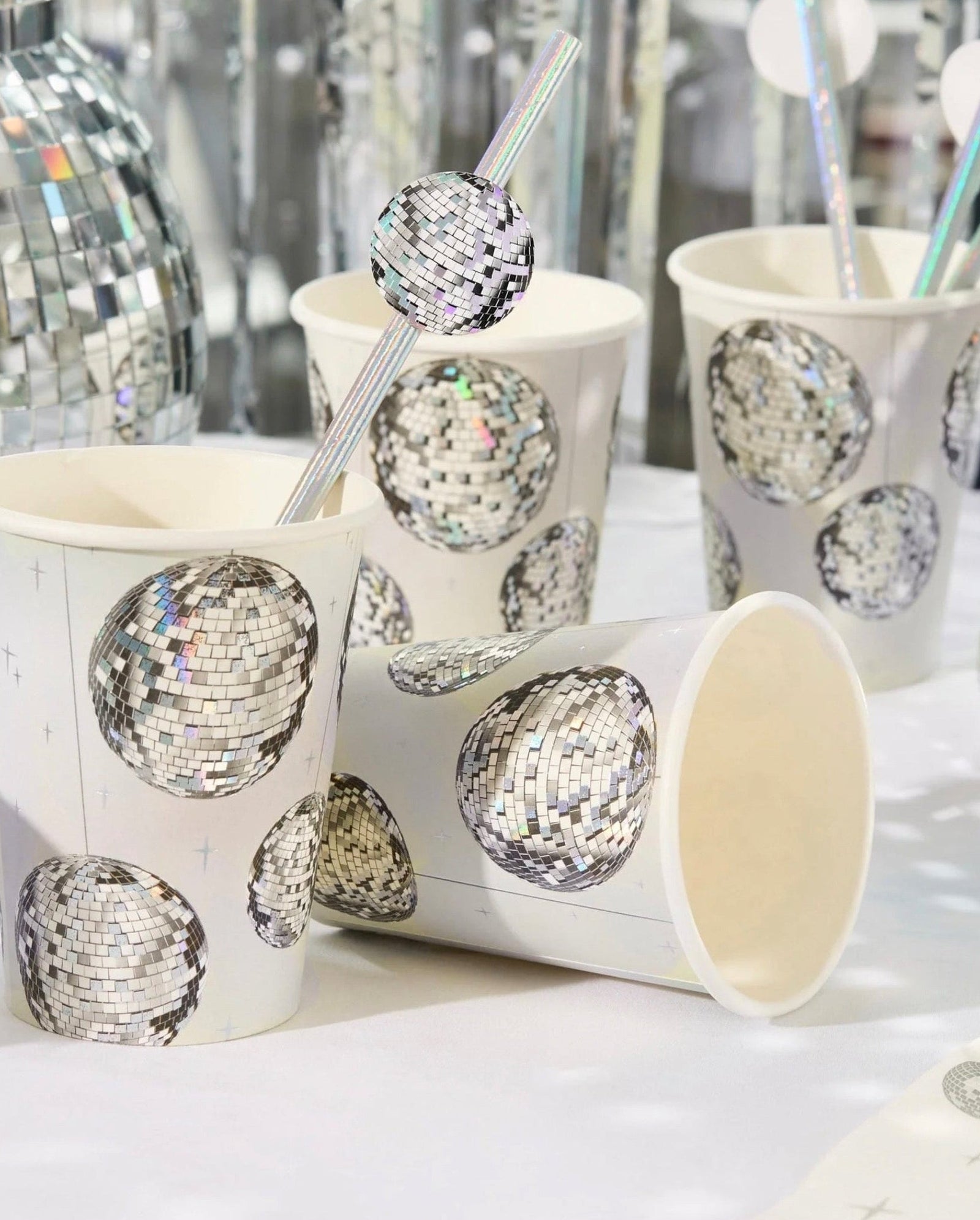 Paper cups with disco ball design and straws on a white surface