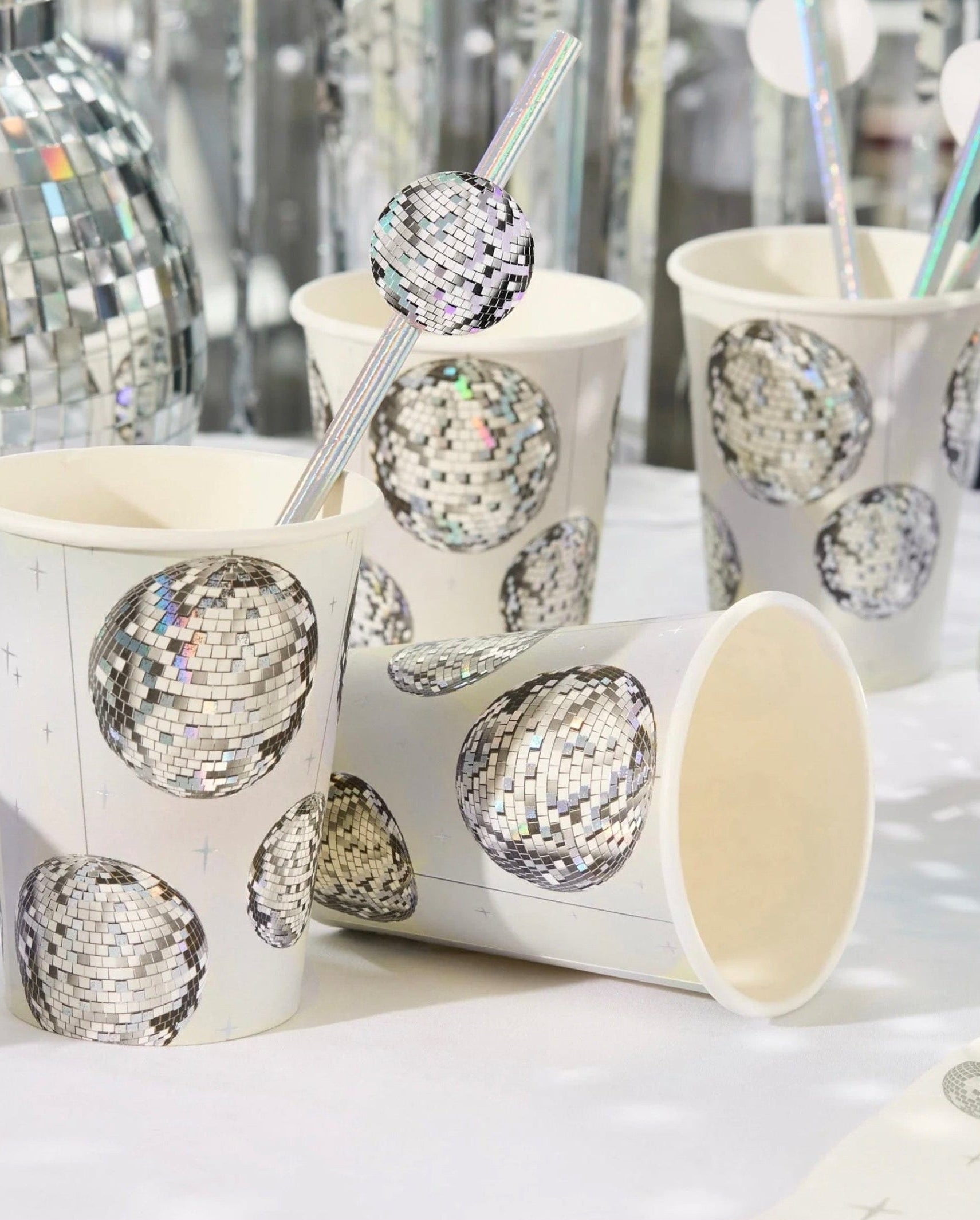 Paper cups with disco ball design and straws on a white surface