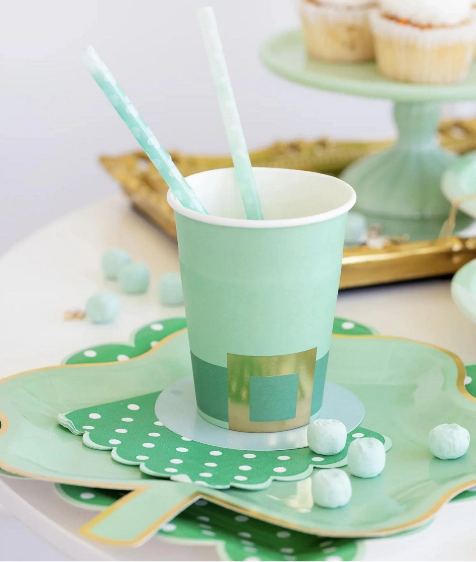 Green paper cup with gold accents on a decorative plate with polka dots